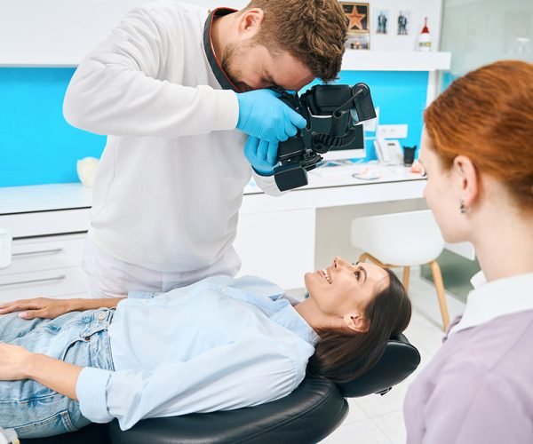 Dental technician doing image of client's teeth using portable x-ray camera, modern tools in private clinic, implantology